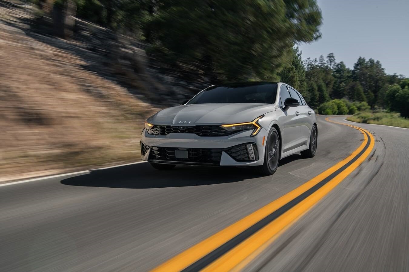 Kia K5 sedan photographed under dramatic city lights