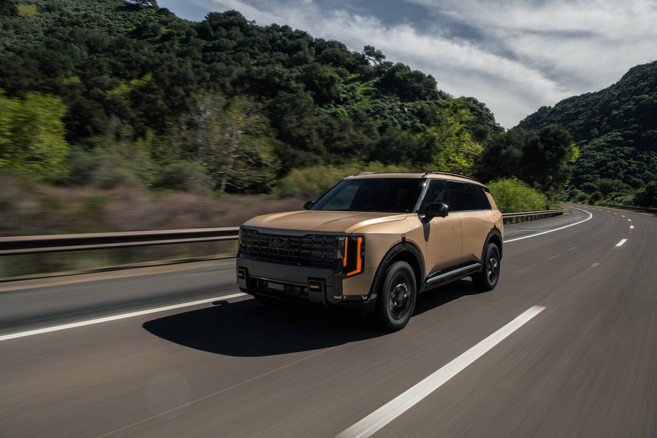 2027 Kia Telluride driving on a tree-lined road